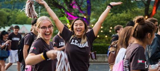 Two female students wearing brown Lehigh t-shirts while celebrating at the Rally