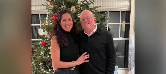 Mariela and Dan Pietrzak smiling in front of Christmas tree