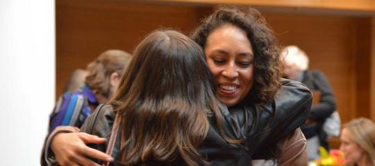 Two women embrace in a hug.