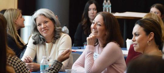 Women smiling at a table during a breakout session