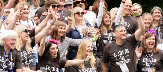 A crowd shot of a group of Lehigh alumni cheering during Reunion Weekend. Heading: Be part of the action.