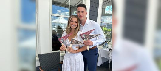 A young couple pose with their arms around each other with each holding Lehigh and Lafayette college flags