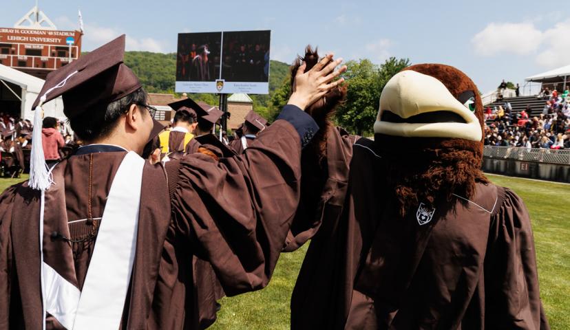 A Lehigh graduate gives a high five to the university mascot, Clutch, during Commencement.