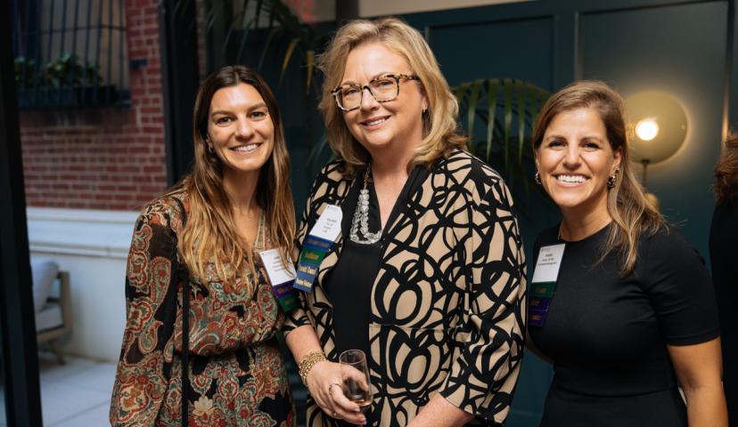 Three women smile for a photo during a networking event.