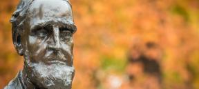 Closeup of the bust of an outdoor Asa Packer sculpture with fall foliage in the foreground