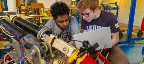 Two students looking into a robotics project together