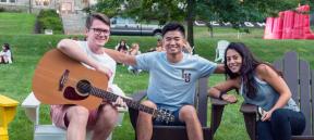 Three Lehigh University students sitting in Adirondacks chairs on the Clayton University Center lawn.