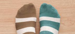 Two feet wearing brown and green mismatched, striped socks