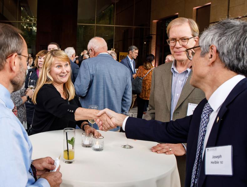 President Joseph J. Helble shaking a woman's hand over a white tablecloth