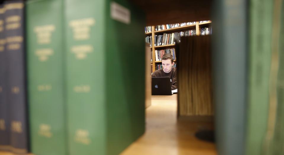 Series of books on a shelf with a student in the background
