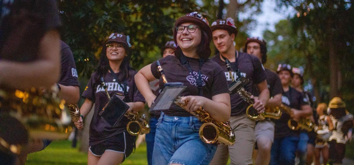 Students in the Marching 97 walking with their instruments and smiling